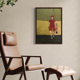 Framed wall art of a female golfer in pink displayed in a floating dark wood frame, modern artwork for home decor on a beige wall above a brown leather chair.