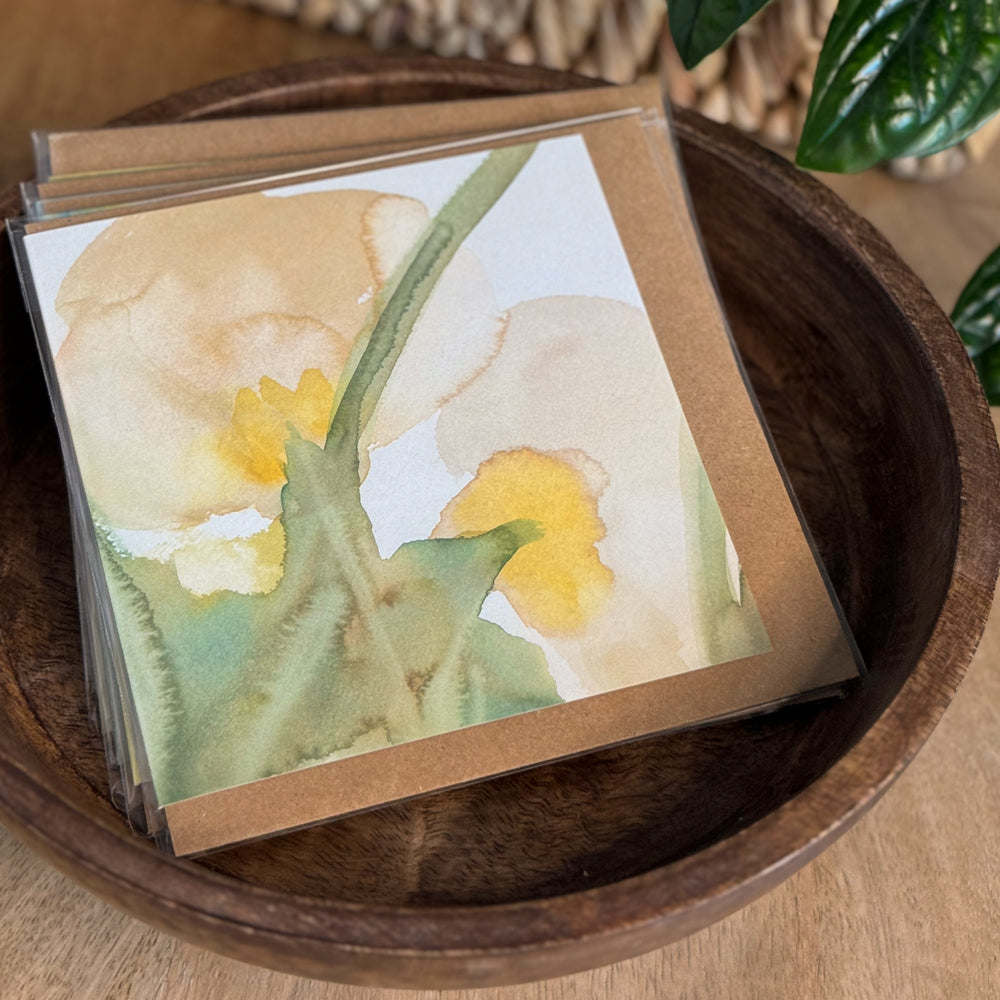Portrait shot of a 6×6 blank watercolor note card “Gentle Anemones” propped on a kraft envelope on a wood tabletop with blurred greenery—perfect blank thank you cards, baby shower thank you cards, graduation thank you cards, wedding note.