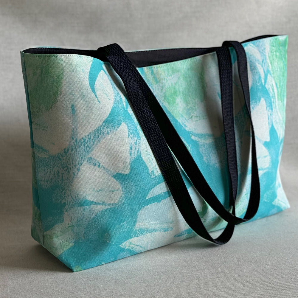 Studio front view of a "Palm Beach" large canvas tote bag, used as a reusable beach bag tote, everyday carryall, or cute tote bag for women. If you like Free People tote bags, then you’ll love this stylish weekender.
